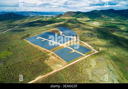 Vue panoramique aérienne de la vaste ferme solaire avec de nombreux panneaux photovoltaïques s'étendant à travers le paysage rural Banque D'Images