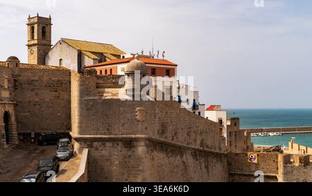 Murs de forteresse en pierre historiques avec tour de guet et clocher de l'église surplombant la ville balnéaire et le port sous ciel clair, archite côtière méditerranéenne Banque D'Images
