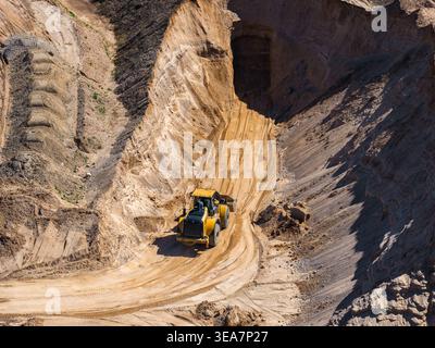 Chargeuse sur pneus aérienne sur piste de transport en terrasses dans une mine à ciel ouvert à midi Banque D'Images
