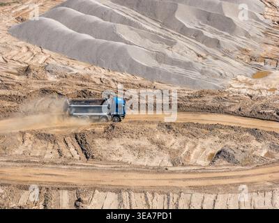 Vue aérienne d'une mine à ciel ouvert avec camion à benne basculante sur une piste de transport en terrasses Banque D'Images