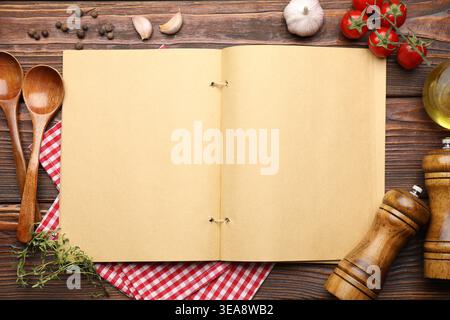 Livre de recettes ouvert, produits, épices et cuillères sur table en bois, pose à plat. Espace pour le texte Banque D'Images