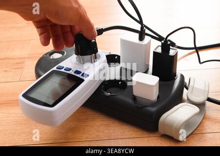 Fiche électrique dans la prise de courant à la maison. Équipement électrique, fils électriques et barrettes d'alimentation dans la maison. Rallonge d'alimentation utilisée. Earth Hou Banque D'Images