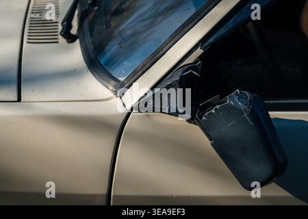 Miroir cassé sur voiture Vintage. Plan détaillé du miroir latéral battu avec fond urbain Banque D'Images
