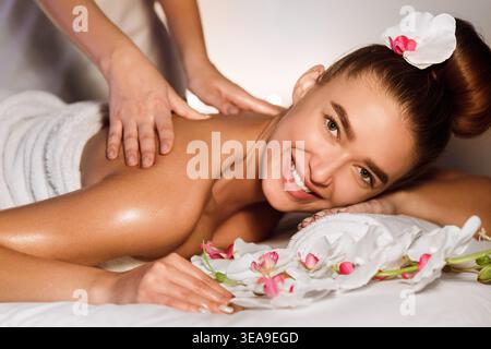Femme appréciant le massage du dos, souriant à la caméra Banque D'Images