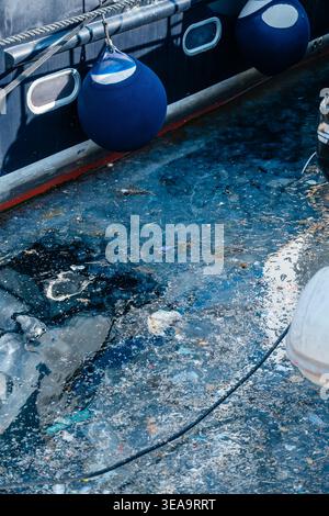 Bateau altéré avec des algues. Peinture décolorée et revêtement d'algues rugueuses sur le bateau près de Weathered Dock Banque D'Images