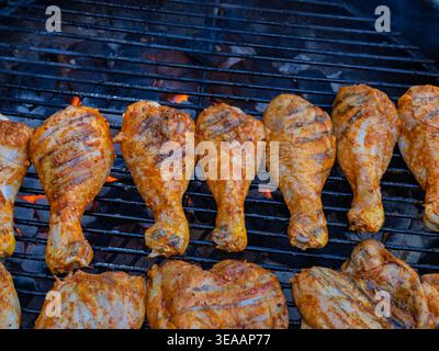 Assortiment de pilons de poulet et de cuisses grésiller sur des charbons chauds éclatants Banque D'Images