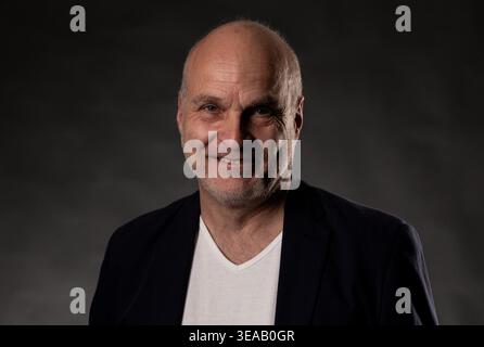 Homme chauve souriant, portant un blazer et un t-shirt, regardant la caméra Banque D'Images