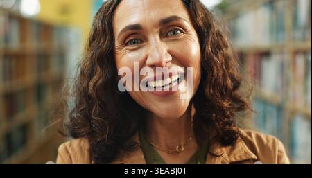 Éducation, portrait ou professeur en bibliothèque avec bonheur, emploi ou confiance en position académique. Sourire, femme mature ou éducateur à l'école avec Banque D'Images