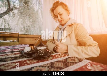 Woman Writing Coffee Shop Notebook - Une jeune femme écrit dans un cahier tout en profitant d'une tasse de café dans un café. Banque D'Images