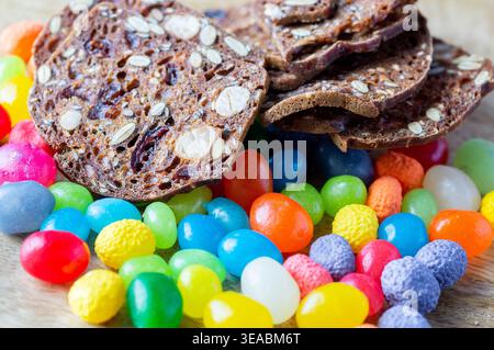 Bonbons colorés à la marmelade sur un fond en bois. Pains croustillants avec des noix, des raisins secs et des graines. Gros plan des pains croustillants sur un fond en bois. Banque D'Images