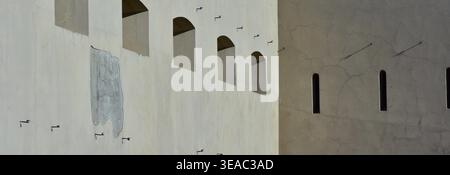 Abstrait architectural de murs de forteresse historiques avec des fenêtres cintrées et des ombres vives. Composition minimaliste du 9e Fort de Kaunas montrant la défense Banque D'Images