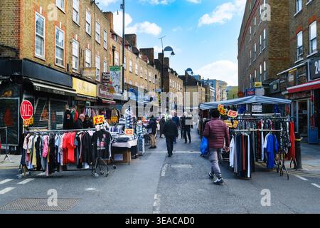 Stands de vêtements occupés avec des panneaux de vente de £2 et £5 au marché Petticoat Lane sur Wentworth Street près de Spitalfields, East London, Angleterre, Royaume-Uni, avec des rangées de Banque D'Images