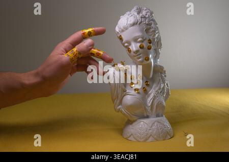 Nature morte conceptuelle : buste de gypse blanc avec des épingles dorées et une main humaine avec des bandages colorés. Thèmes de la santé mentale, du traumatisme et de la guérison. Banque D'Images