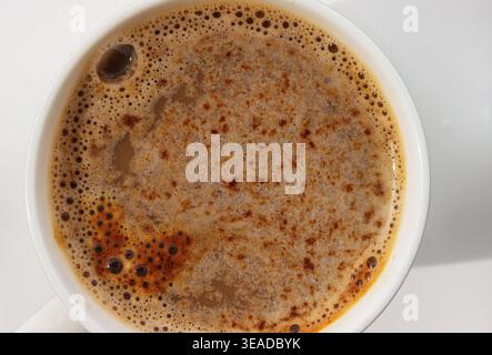 Macro vue de dessus de la texture de la crème de café dans la tasse sur fond blanc.mise au point sélective. Copier l'espace Banque D'Images