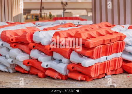 Barrières en plastique orange et blanc disposées sur un sol poussiéreux, préparant la construction de routes et le projet de développement urbain Banque D'Images