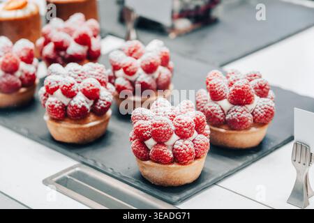 Tartes aux framboises présentant des baies fraîches et du sucre en poudre, prêtes à la vente dans une confiserie ou une pâtisserie Banque D'Images