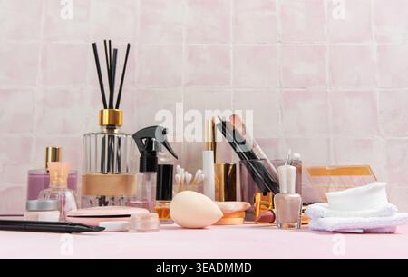 Divers articles de beauté et de soins personnels disposés sur un fond rose clair, prêts à l'emploi Banque D'Images