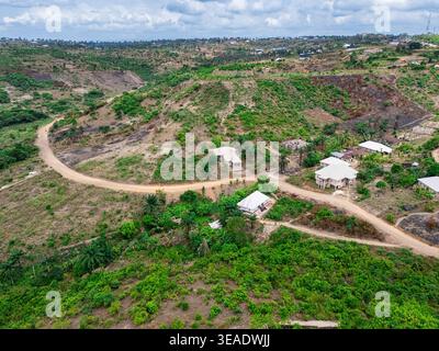 Vue aérienne de chemins de terre sinueux coupant à travers une végétation clairsemée et des bâtiments dispersés sur un terrain vallonné, Asaga, Abia, Nigeria. Banque D'Images
