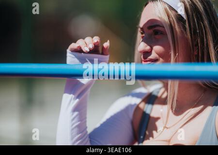 Jeune athlète femme appuyée sur la balustrade bleue à l'extérieur dans un portrait d'été réfléchi Banque D'Images