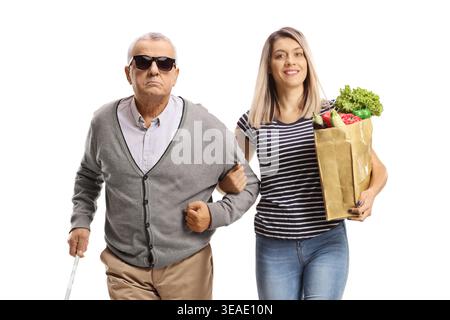 Femme portant un sac d'épicerie et aidant un homme aveugle âgé isolé sur fond blanc Banque D'Images