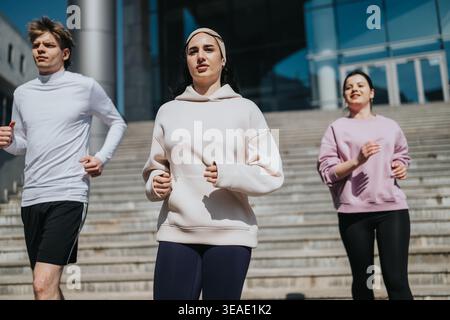 Trois personnes faisant du jogging ensemble à l'extérieur sur des marches urbaines pour le fitness en groupe et un style de vie actif Banque D'Images