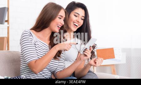Deux amis apprécient un moment amusant tout en utilisant leur smartphone à la maison Banque D'Images