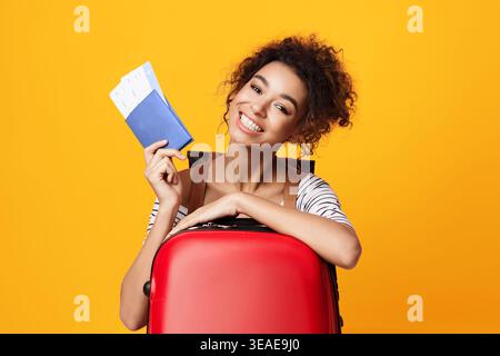 Happy Traveler tenant passeport et billets avec valise rouge en arrière-plan lumineux Banque D'Images