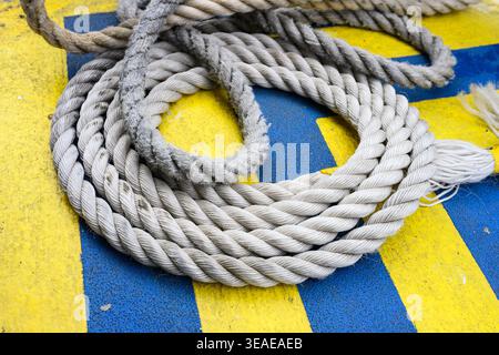 Corde enroulée de manière lâche sur une surface texturée bleue et jaune Banque D'Images