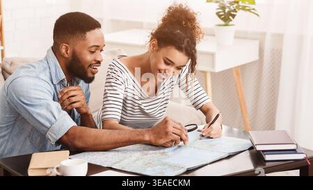 Couple planifier des vacances ensemble à la maison tout en regardant une carte dans l'après-midi Banque D'Images