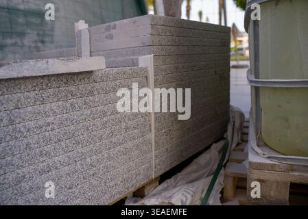 Gros plan de dalles de granit ou de pierre empilées sur des palettes sur le chantier de construction. Matériaux de construction préparés pour l'installation, stockage extérieur avec equipme Banque D'Images