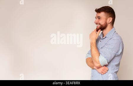 Jeune homme souriant et penser à la voiture sur l'espace libre Banque D'Images