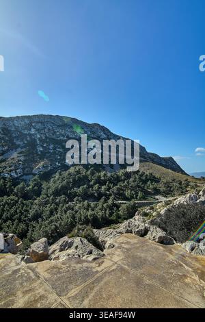 Une vue verticale large d'un point de vue en pierre surplombant les pics de calcaire accidentés et les forêts denses de pins des montagnes de la Serra de Tramuntana sous un Banque D'Images