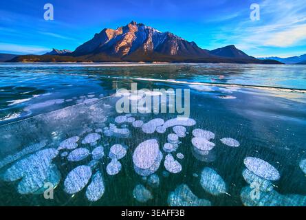 Bulles de glace gelées du lac et reflets des montagnes enneigées dans le paysage hivernal Banque D'Images