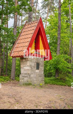 Un beffroi se dresse dans un cadre forestier aux rochers de grès de Prachovske. La structure présente un toit coloré et est entourée de grands arbres. Il marque un domaine d'importance historique. Banque D'Images