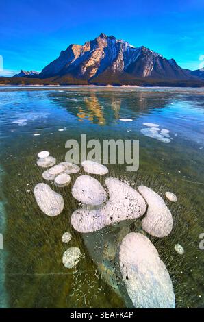 Bulles de méthane gelées et reflets majestueux des montagnes sur la surface du lac Winter Banque D'Images