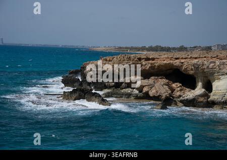 Falaises côtières rocheuses avec grottes marines et océan bleu Banque D'Images