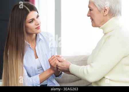 Fille soutenant sa mère senior, holding hands Banque D'Images
