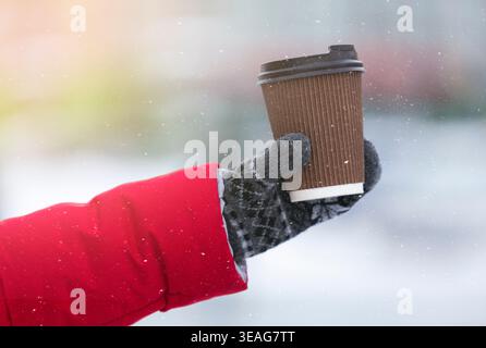 Female hand in glove holding cup avec du thé chaud, du café Banque D'Images