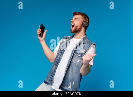 Cool jeune homme chantant en casque sur l'arrière-plan Banque D'Images