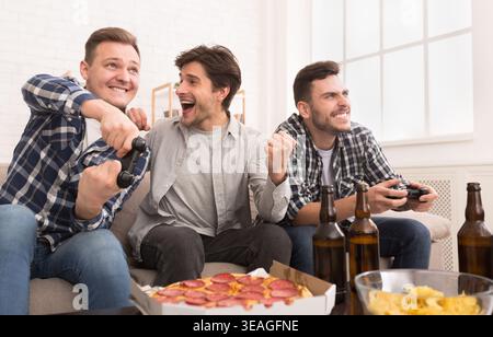 L'attention des joueurs. Les hommes excités à jouer à des jeux vidéo à la maison Banque D'Images
