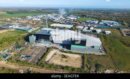 Vue aérienne de l'installation de récupération d'énergie avec son architecture moderne et sa cheminée haute entourée de bâtiments industriels et de champs verts Li Banque D'Images