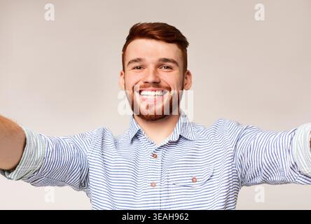 Beau jeune homme tenir l'appareil photo et faire selfies Banque D'Images