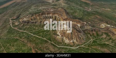 Vue aérienne des majestueuses formations rocheuses en couches et des falaises abruptes s'élevant du paysage vert de steppe à Mangistau, région de Mangystau, Kazakhstan Banque D'Images