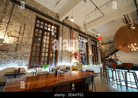 Jakarta, Indonésie - 3 février 2026 - vue intérieure du café Acaraki avec murs en briques blanches apparentes, grandes fenêtres encadrées en bois, lumière chaude Banque D'Images