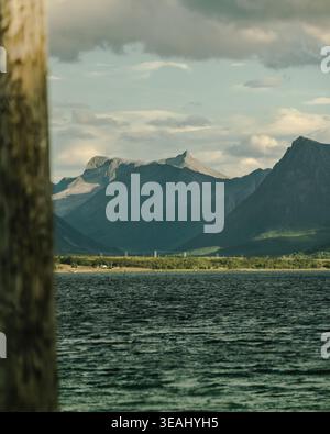 Une composition créative utilisant un tronc d'arbre au premier plan pour encadrer un paysage pittoresque de fjord norvégien et de montagne, ajoutant de la profondeur et un encadrement naturel Banque D'Images