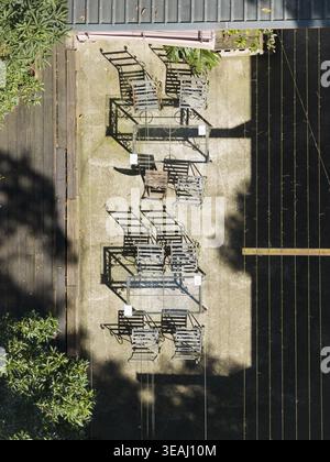 Vue aérienne des sièges de café en plein air et des tables en verre sur un patio en béton avec de longues ombres et un feuillage vert luxuriant à Taiwan. Banque D'Images
