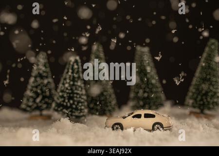 Une petite voiture blanche navigue à travers un paysage hivernal enneigé, en passant par des arbres couverts de neige. Banque D'Images
