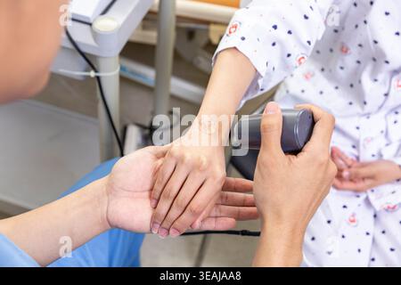Un médecin applique un bandage sur le poignet d'un patient dans un cadre hospitalier. Banque D'Images