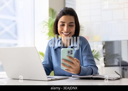 Femme d'affaires à l'aide d'un smartphone est assis au bureau avec ordinateur portable et ordinateur portable Banque D'Images