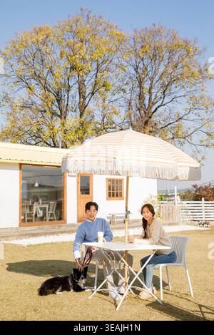 Un jeune couple profite d'un café ensemble par une journée ensoleillée dans un charmant café en plein air. Banque D'Images